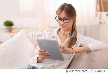 Lady Using Digital Tablet Sitting On Couch Indoor 59758211
