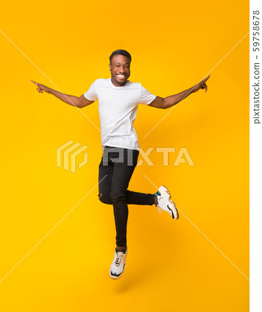 Cheerful Black Guy Jumping Having Fun Over Yellow Background 59758678