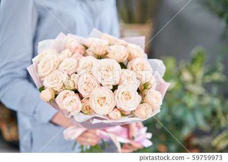 Mono bouquet of Bush roses in womans hands. European floral shop. the work of the florist at a Mono bouquet of Bush roses in womans hands. European floral shop. the work of the florist at a 59759973