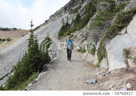 Man walking along a trail near Mount Rainier Man walking along a trail near Mount Rainier 59768917