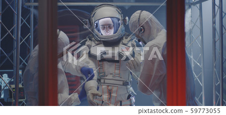 Scientist helping astronaut to put on gloves Scientist helping astronaut to put on gloves 59773055