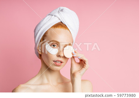 Shot of young woman applies eye patches and holding cosmetic sponge 59773980
