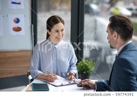 Smiling assistant talking to businessman and making some notes in the morning 59774391