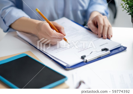 Close up of businesswoman filling tax declaration while sitting at the table 59774392