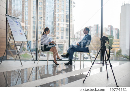 Investor giving the interview to famous journalist sitting near window Investor giving the interview to famous journalist sitting near window 59774581