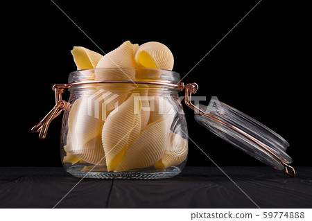 Jar of conchiglie pasta shell on wooden table isolated on black background 59774888