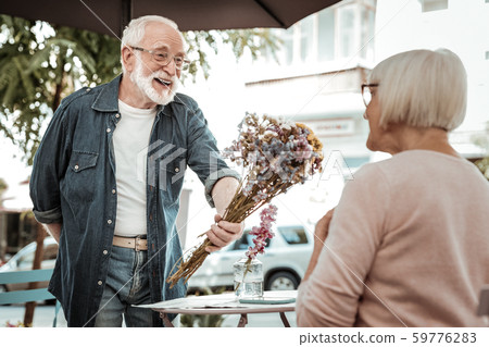 Positive bearded man giving a flower bouquet 59776283