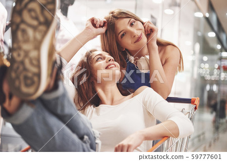 Young women have fun with a supermarket basket in the evening. Attractive young woman spend time Young women have fun with a supermarket basket in the evening. Attractive young woman spend time 59777601
