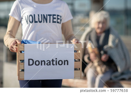 Close up of young kind volunteer holding box with donation 59777638