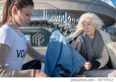 Woman looking at clothing while volunteer bringing donation Woman looking at clothing while volunteer bringing donation 59777912