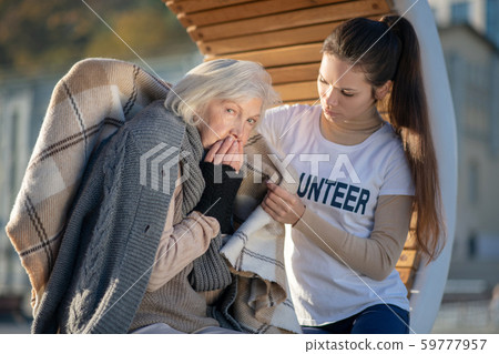 Homeless miserable woman feeling cold thus volunteer supporting her Homeless miserable woman feeling cold thus volunteer supporting her 59777957