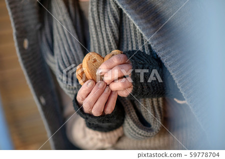 Poor homeless woman wearing scarf holding crackers Poor homeless woman wearing scarf holding crackers 59778704