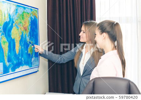Two business-like young women plot a route on a 59780420