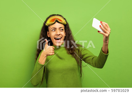 African-american young woman's portrait in ski mask on green background African-american young woman's portrait in ski mask on green background 59781029