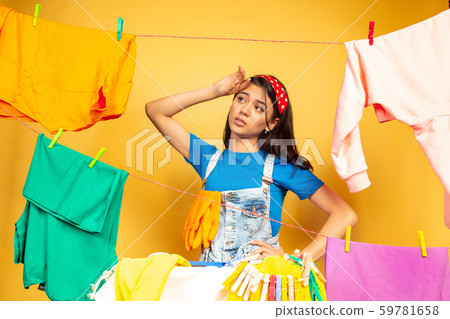 Funny and beautiful housewife doing housework on yellow background Funny and beautiful housewife doing housework on yellow background 59781658