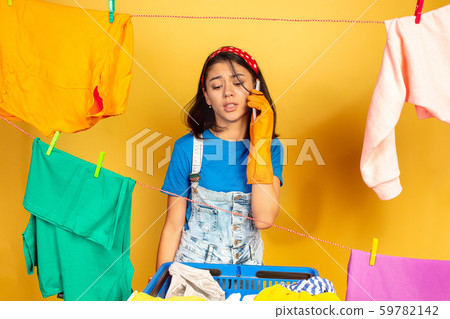 Funny and beautiful housewife doing housework on yellow background 59782142