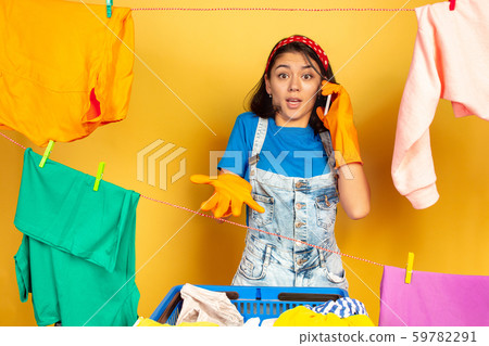 Funny and beautiful housewife doing housework on yellow background Funny and beautiful housewife doing housework on yellow background 59782291