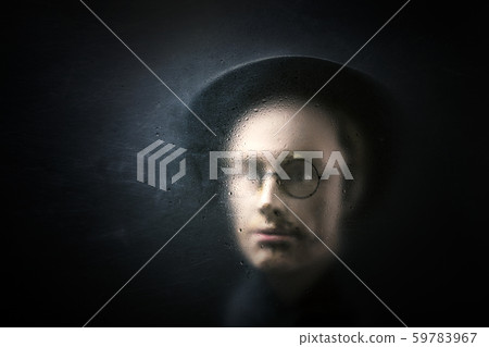 Mystery figure with hat and glasses behind a dusty scratched glass. 59783967