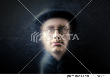 Mystery figure with hat and glasses behind a dusty scratched glass. 59783969