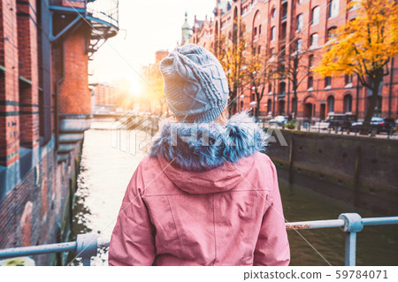 Back view of adult woman tourist enjoying autumn beautiful sunset scene of Speicherstadt historic 59784071