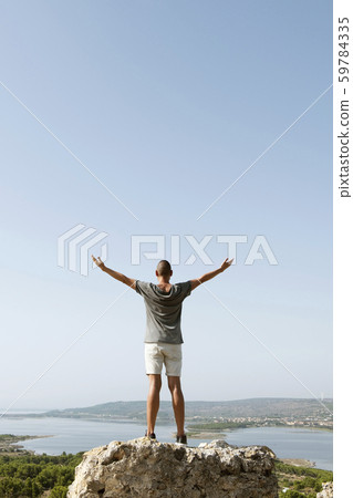 man with his arms in the air on the top of a rock man with his arms in the air on the top of a rock 59784335