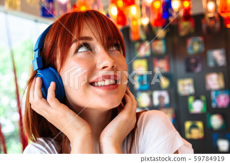 Happy girl listens to music on headphones in cafe Happy girl listens to music on headphones in cafe 59784919