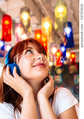 Happy girl listens to music on headphones in cafe Happy girl listens to music on headphones in cafe 59784920