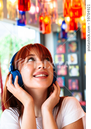 Happy girl listens to music on headphones in cafe Happy girl listens to music on headphones in cafe 59784921