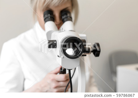 Female blond doctor gynecologist looks through a 59786867