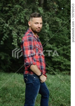 Outdoor portrait of relaxed handsome young man with beard in the park on green trees background Outdoor portrait of relaxed handsome young man with beard in the park on green trees background 59790453