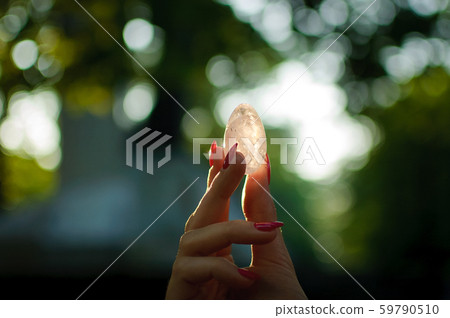 Female hand with transparent amethyst quartz yoni egg for vumfit, imbuilding or meditation. Shining Female hand with transparent amethyst quartz yoni egg for vumfit, imbuilding or meditation. Shining 59790510