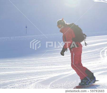 Snowboarder descends on snowy ski slope prepared 59791683