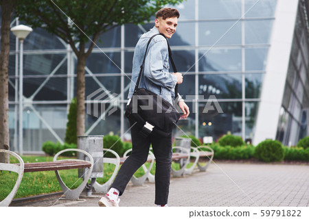 Young handsome man with a bag on his shoulder in a hurry to the airport Young handsome man with a bag on his shoulder in a hurry to the airport 59791822
