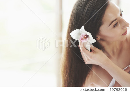 Beautiful young woman posing with orchid. Skin care treatment 59792026