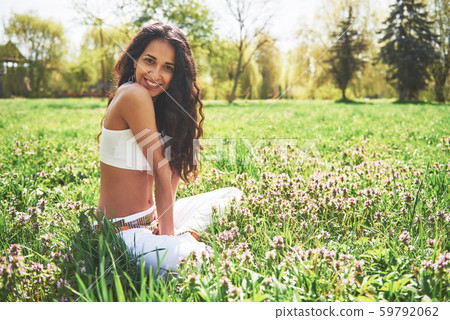 Practicing yoga of a beautiful girl in the morning on herbs under the sun's words. 59792062