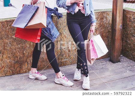 Two young woman carrying shopping bags while walking the street after visiting the stores Two young woman carrying shopping bags while walking the street after visiting the stores 59792322