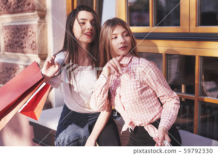 Two women talking after shopping on the street near the window Two women talking after shopping on the street near the window 59792330
