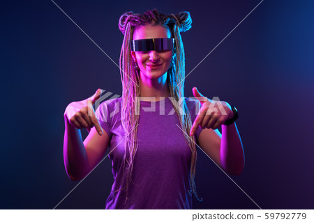 Happy girl with pigtails in sunglasses looking at camera in neon light Happy girl with pigtails in sunglasses looking at camera in neon light 59792779