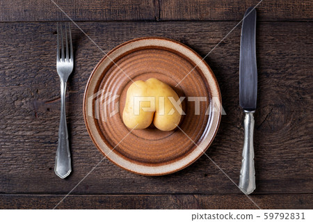 Dieting concept - single potato in the form of buttocks on an empty plate Dieting concept - single potato in the form of buttocks on an empty plate 59792831