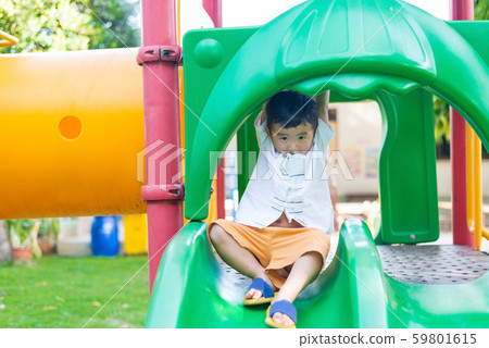 Little Asian kid playing slide at the playground 59801615
