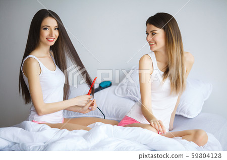 Attractive woman loking at her sister while she combing hair Attractive woman loking at her sister while she combing hair 59804128