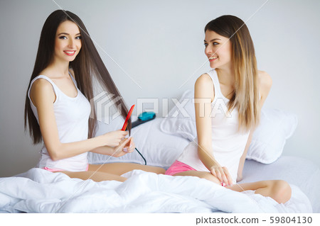 Attractive woman loking at her sister while she combing hair Attractive woman loking at her sister while she combing hair 59804130