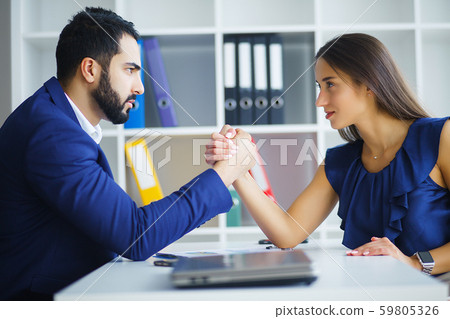 Man and woman arm wrestling on table Man and woman arm wrestling on table 59805326