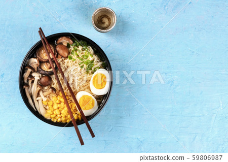 Ramen. Soba noodles with boiled eggs, shiitake mushrooms, and vegetables, top shot on a blue Ramen. Soba noodles with boiled eggs, shiitake mushrooms, and vegetables, top shot on a blue 59806987