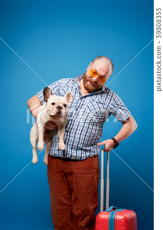 Male with bulldog and luggage on empty blue background Male with bulldog and luggage on empty blue background 59808355