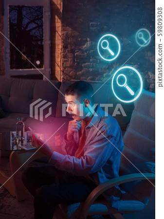 Man using gadget and receive neon notifications at home at night 59809308