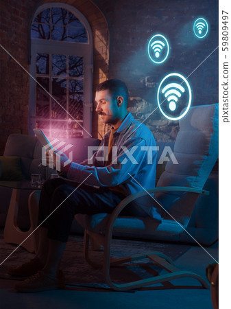 Man using gadget and receive neon notifications at home at night 59809497