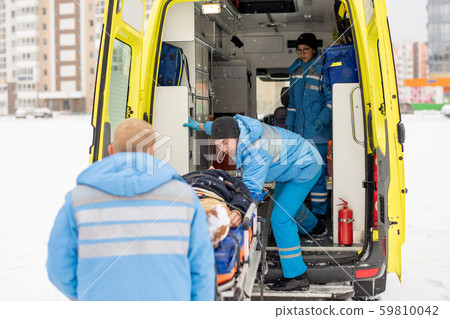Paramedics getting stretcher with fixed unconscious man into ambulance car Paramedics getting stretcher with fixed unconscious man into ambulance car 59810042