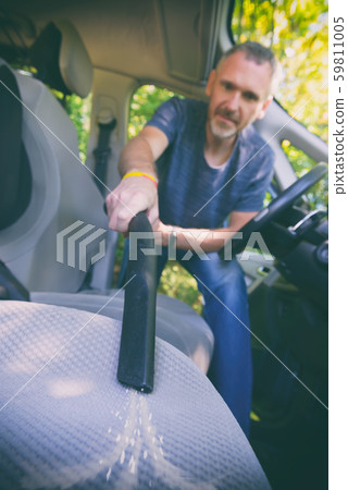 Man hoovering a seat in car 59811005