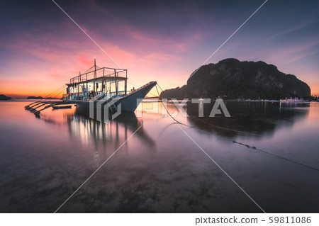Banca boat at Corong Corong beach on low tide shallow water in twilight lit by sunset light, El Nido Banca boat at Corong Corong beach on low tide shallow water in twilight lit by sunset light, El Nido 59811086